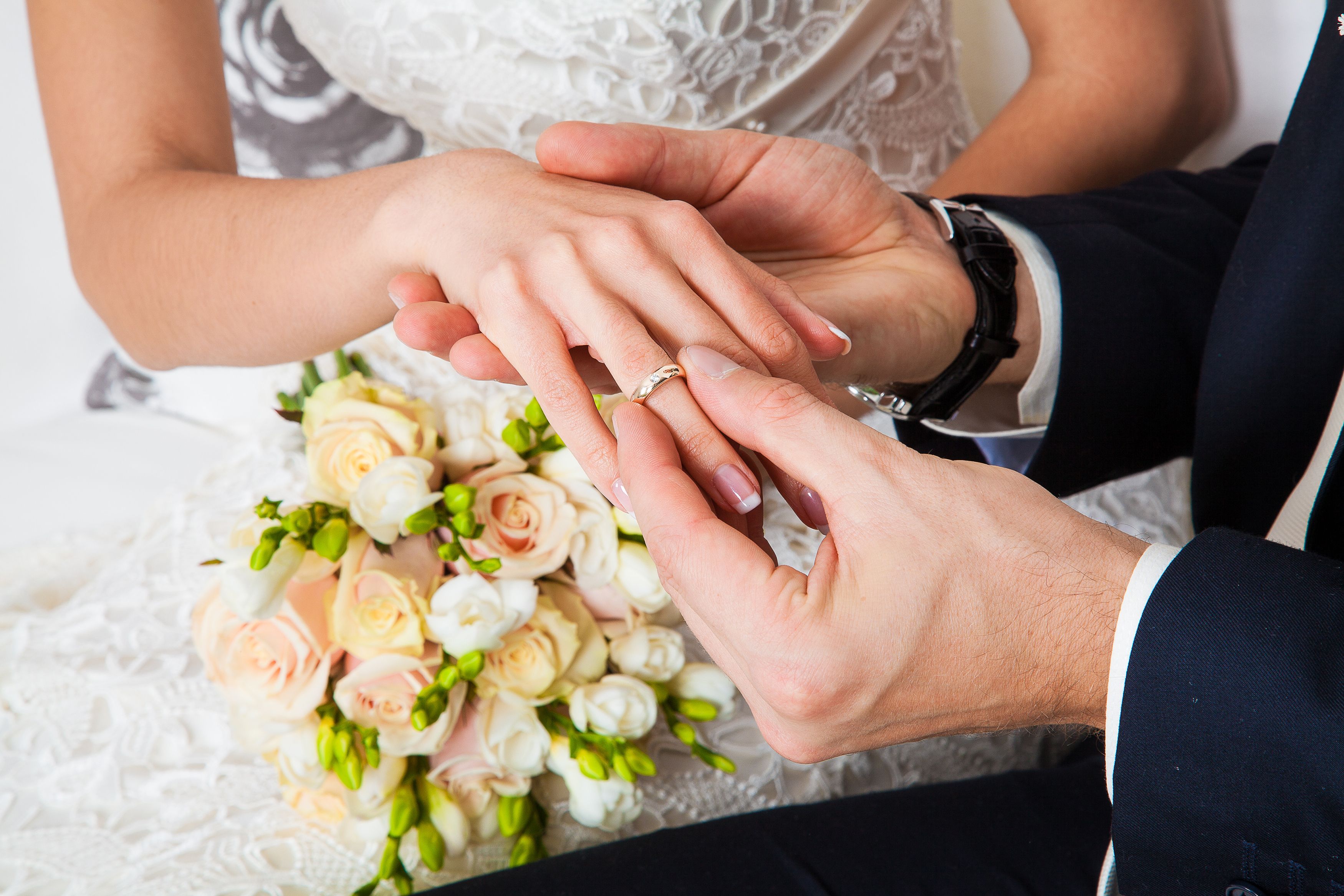 Зарегистрироваться брак. Свадебные кольца на руках. Обручальные кольца жених и невеста. Невеста на руках у жениха. Жених одевает кольцо невесте.