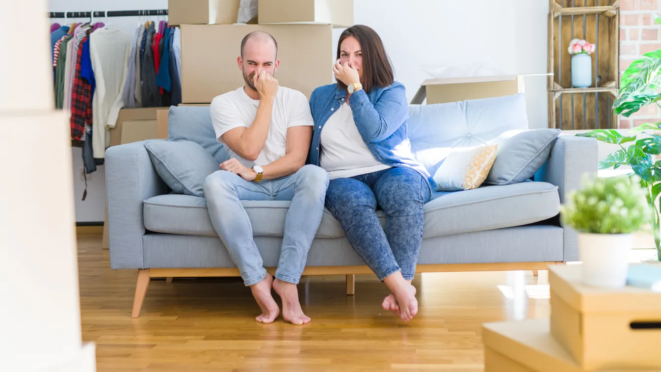 Young,Couple,Sitting,On,The,Sofa,Arround,Cardboard,Boxes,Moving