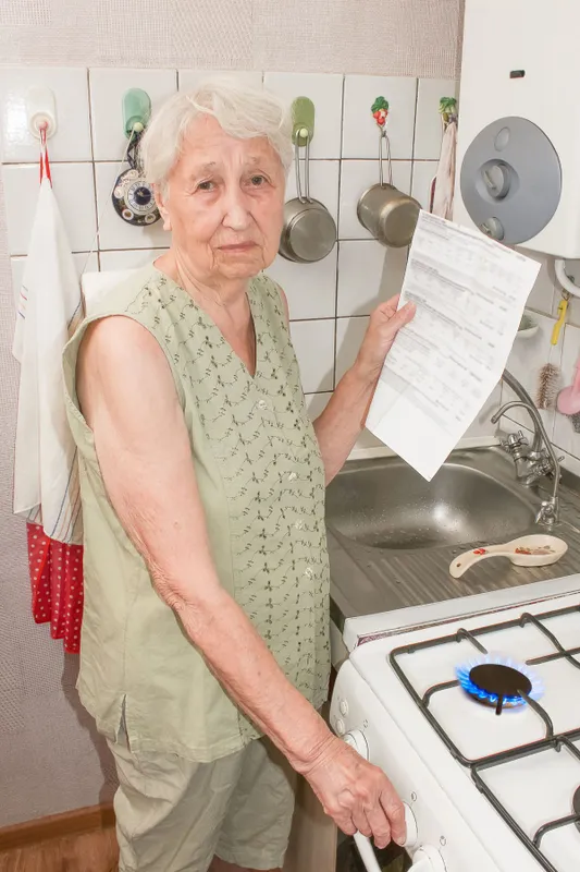 The,Sad,Senior,Woman,At,Home,And,Examines,Gas,Bill.