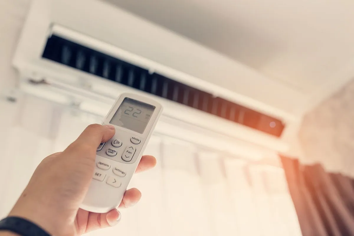 Air,Conditioner,Inside,The,Room,With,Woman,Operating,Remote,Controller.