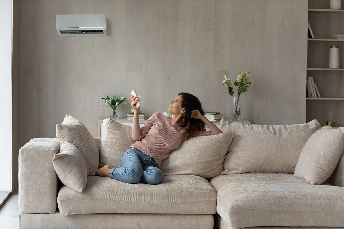 Smiling,Woman,Using,Air,Conditioner,Remote,Controller,,Relaxing,On,Comfortable