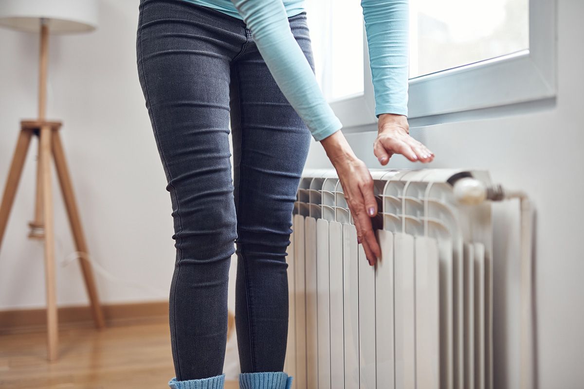 Woman,Heating,Her,Hands,On,The,Radiator,During,Cold,Winter