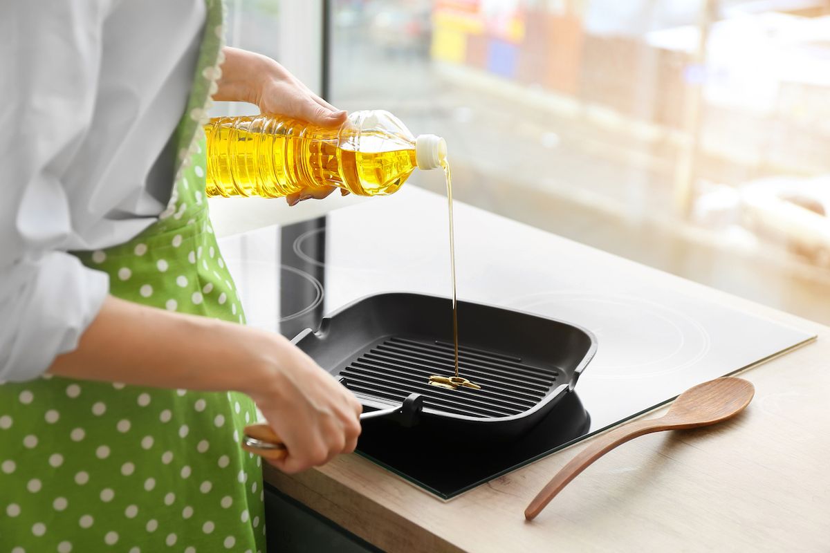 Woman,Pouring,Sunflower,Oil,Onto,Frying,Pan,In,Kitchen