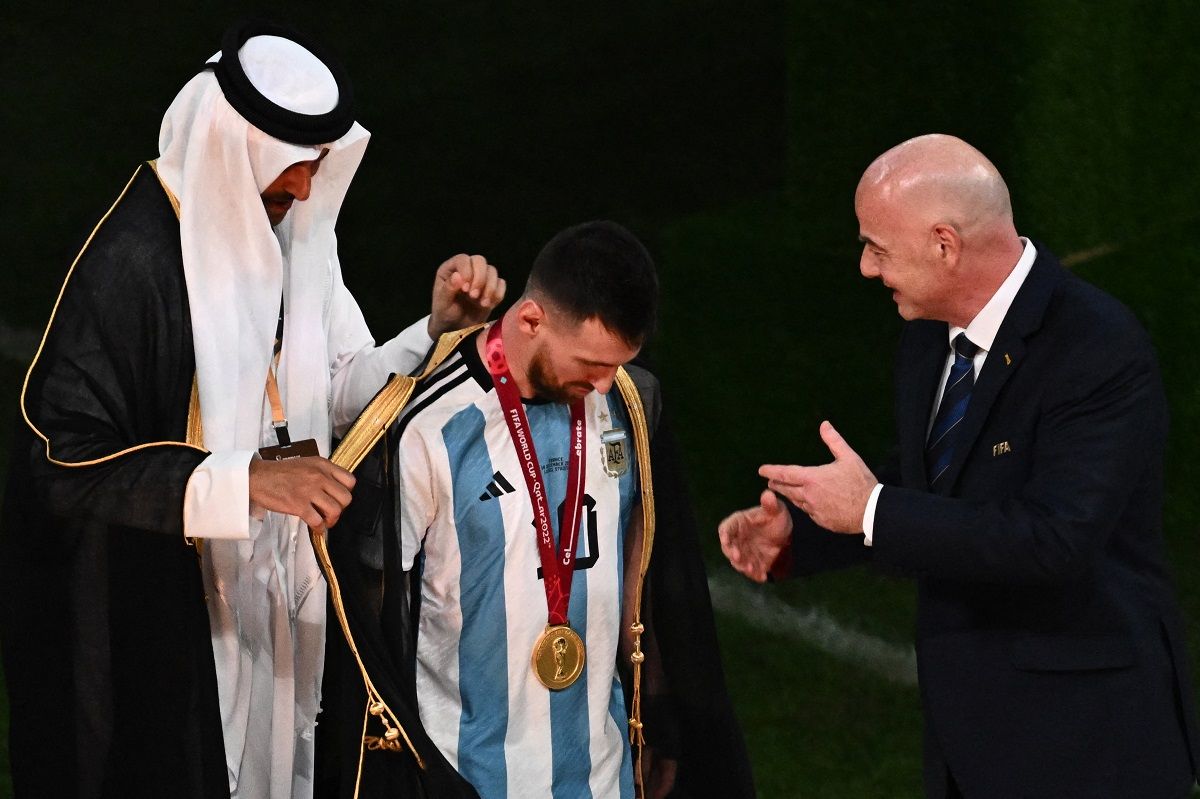 Tamím bin Hamád Ál Száni emír (balra) maga öltöztette be Messit, mellettük Gianni Infantino FIFA-elnök
