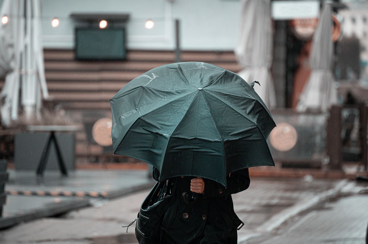 Woman,Walking,In,The,City,With,Green,Umbrella,On,Rainy