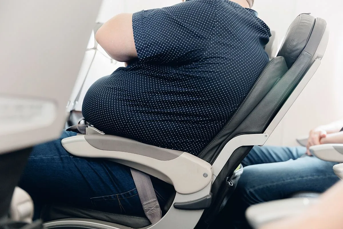 Fat,Obese,Man,Passenger,Fastening,Seat,Belt,On,Airplane,,Problem