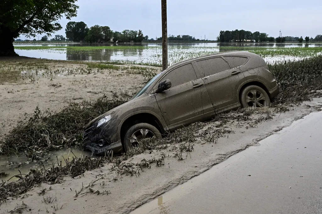 A car wich was washed away by muddy waters is pictured in a ditch on May 20, 2023 near the village of Coccolia, Ravenna, after floodwaters hit the Emilia-Romagna region. The toll from floods that have devastated Italy's Emilia Romagna region rose to 14 on May 19, amid calls for the government to revive an abandoned project to mitigate the impact of natural disasters. (Photo by Andreas SOLARO / AFP)