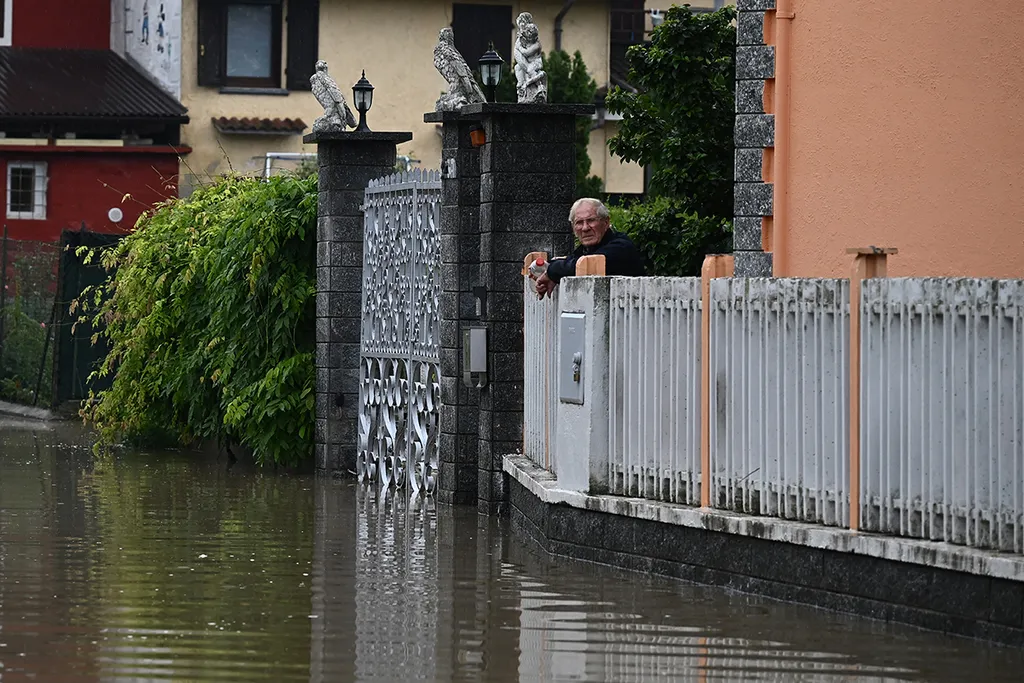 A photo taken on May 21, 2023 shows a resident viewing a flooded street in the village of Carde, Cuneo, near Turin in northwestern Italy, after the river Po came out of its banks. More than 36,000 people have now been forced from their homes by deadly floods in northeast Italy, regional officials said, as rising waters swallowed more houses and fresh landslides isolated hamlets. Violent downpours earlier this week killed 14 people, transforming streets in the cities and towns of the Emilia Romagna region into rivers. (Photo by Marco BERTORELLO / AFP)