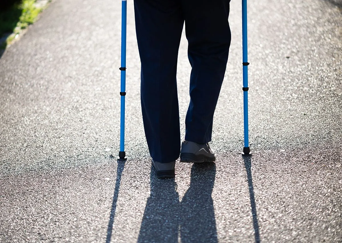 Rear,View,Of,Senior,Male,Walking,Using,Walking,Sticks,On