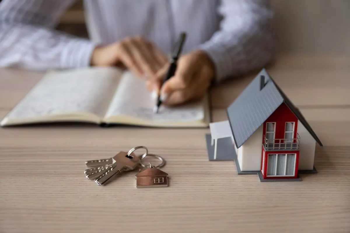 Crop close up businesswoman Real Estate Agent taking notes, paper house model