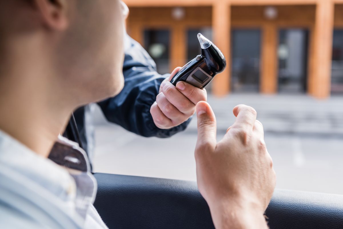 Cropped,View,Of,Policeman,Giving,Breathalyzer,To,Driver,In,Car,