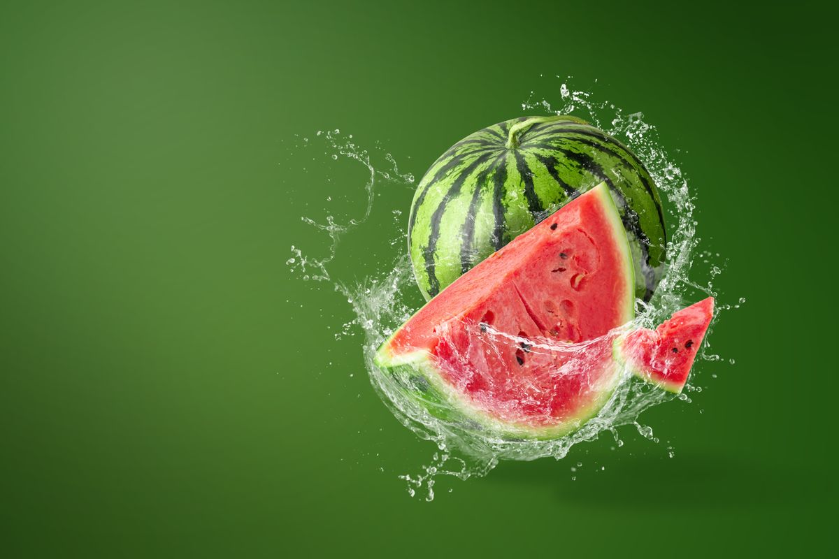 Water,Splashing,On,Sliced,Of,Watermelon,On,Green,Background.