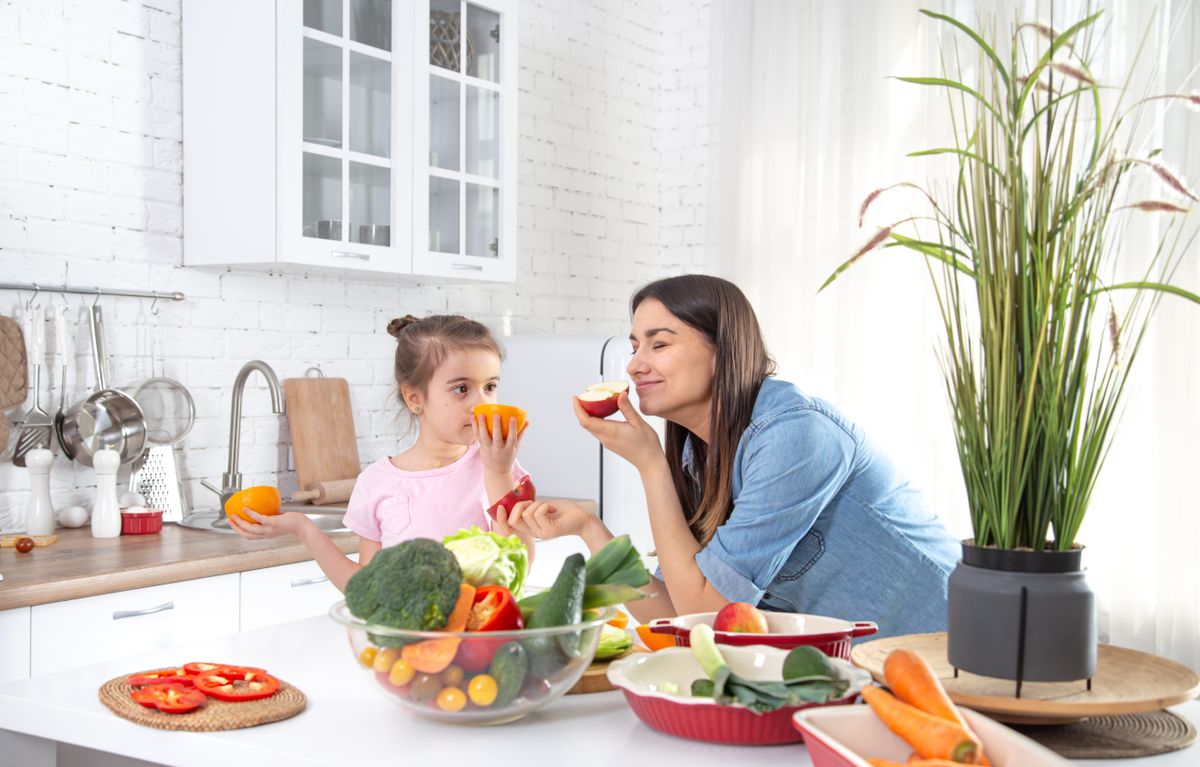 Mom and daughter in the kitchen with fruits and vegetables.