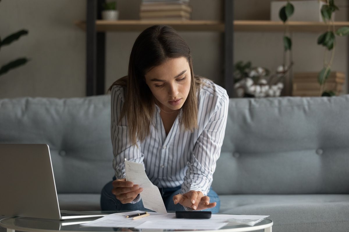 Busy millennial female focused on accounting paperwork at home office