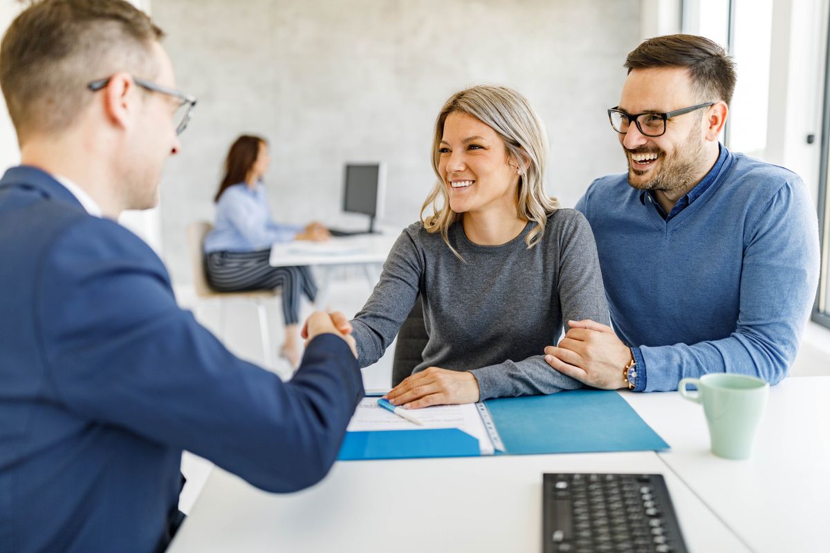 Happy couple came to an agreement with their financial advisor in the office.