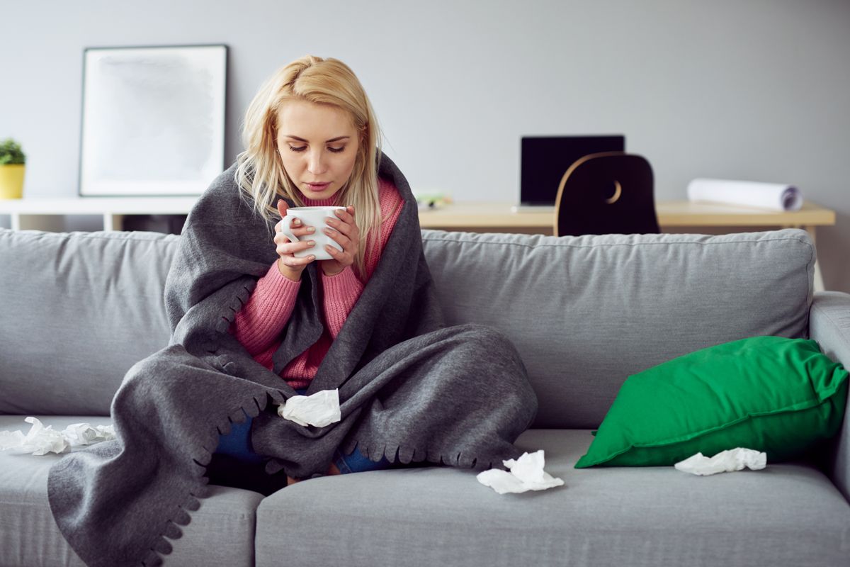 Young,Sick,Woman,Sitting,On,Sofa,Drinking,Tea