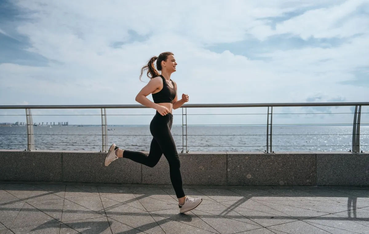 edzés Young,Woman,Jogging,Along,A,Waterfront,Path,,Dressed,In,Black