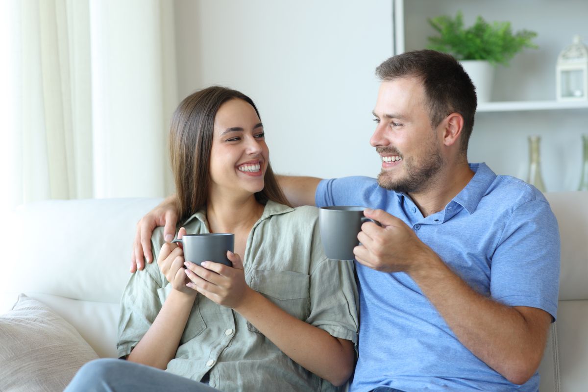 Happy,Couple,Looking,Each,Other,Sitting,On,A,Couch,At