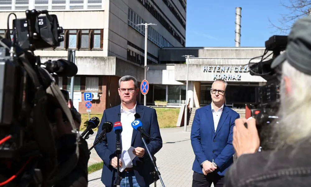 Takács Péter, a Belügyminisztérium egészségügyi államtitkára (b) sajtótájékoztatót tart a kórházak és rendelõintézetek felújítása elmaradásának okáról Szolnokon, a Jász-Nagykun-Szolnok Vármegyei Hetényi Géza Kórház-Rendelõintézet elõtt 2025. április 13-án. Takács Péter közülte, hogy több tucat kórház és rendelõintézet – köztük a szolnoki Hetényi Géza kórház – felújítását állította meg a Tisza Párt és Brüsszel “sunyi alkuja”. Jobbról Piroska Miklós, a Hetényi Géza Kórház-Rendelõintézet fõigazgatója. MTI/Mészáros János