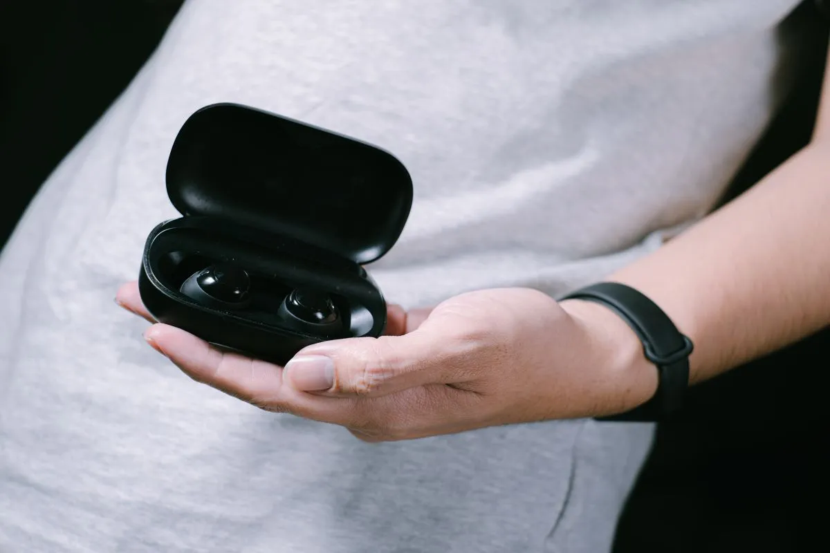 A,Hand,Of,Man,Is,Holding,Black,Wireless,Earphones,In