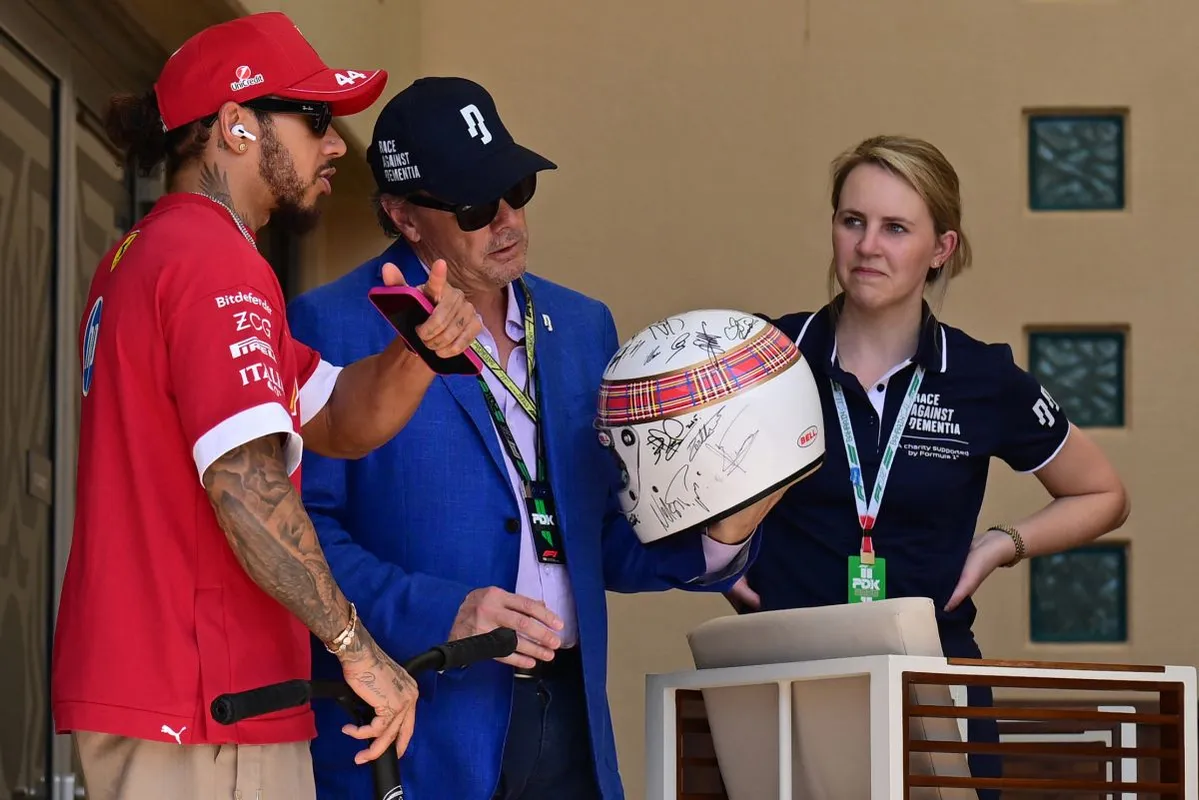A másik 7-szeres F1-világbajnok, Lewis Hamiltonnak (balra) Stewart fia mutatja a Schumacher szignózta sisakot