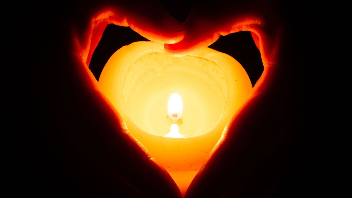 Closeup shot of human hands holding a small candle, gyász, gyertya, 