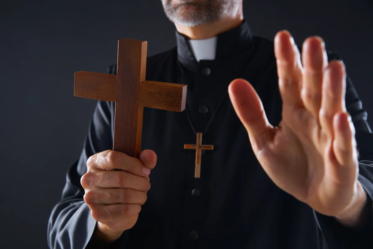 Priest,Holding,Cross,Of,Wood,Praying,In,Foreground