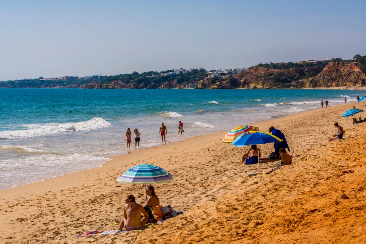 Beachgoers at Red sandstone cliffs of Praia da Falesia, Albufeira District, Algarve, Portugal
