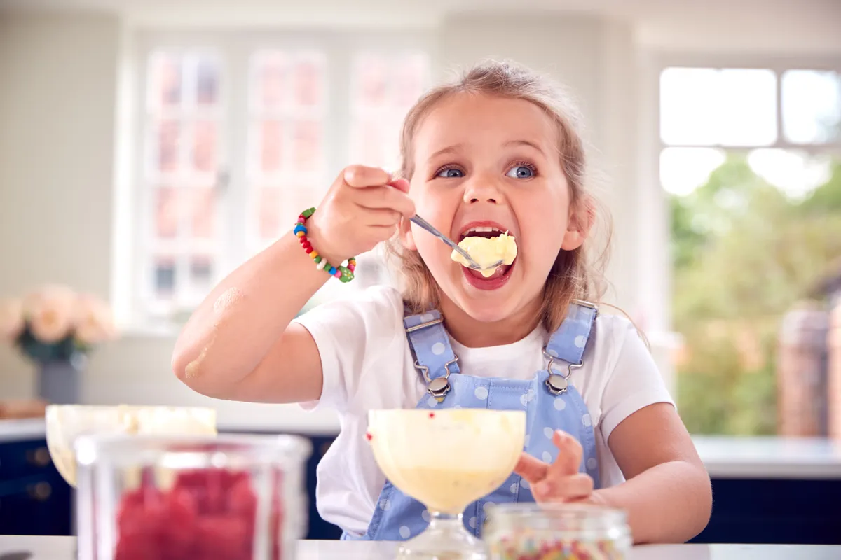 Young,Girl,In,Kitchen,Eating,Ice,Cream,Dessert,With,Spoon