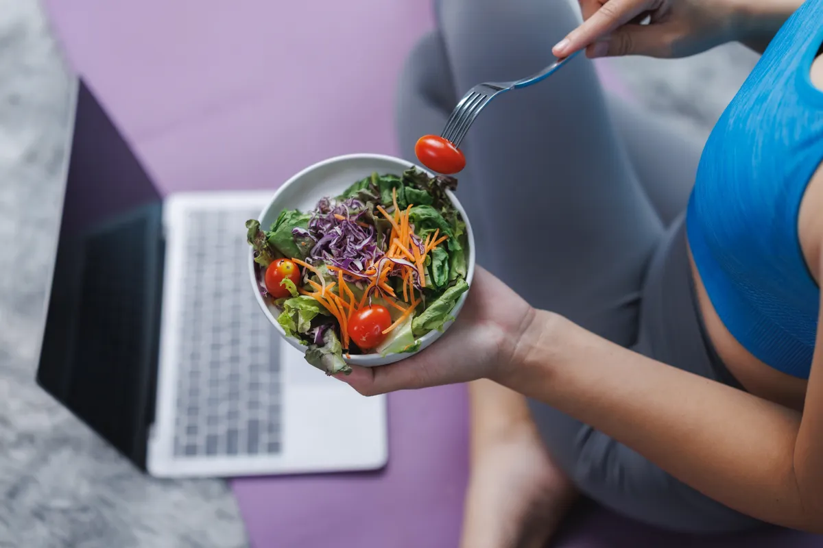 Young,Woman,Eating,Healthy,Salad,While,Working,From,Home,On