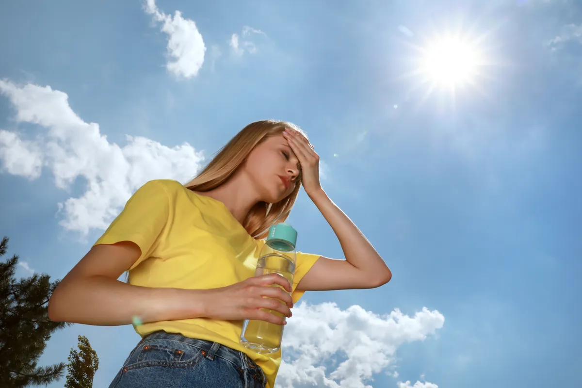 Woman,With,Bottle,Of,Water,Suffering,From,Heat,Stroke,Outdoors