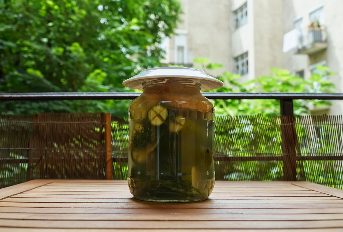 Egy üveg kovászos uborka a kerti asztalon