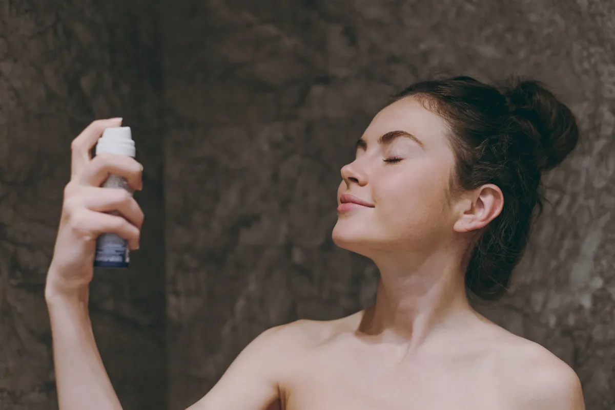 fiatal nő, sminkfixáló spray, barna haj, konty