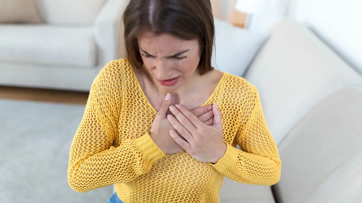 Young woman having chestpain,Acute pain, possible heart attack.Effect of stress and unhealthy lifestyle concept.