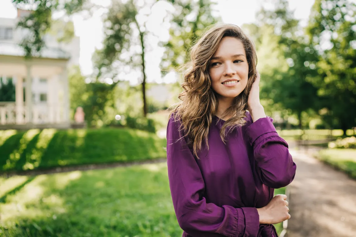 Lila ruhát viselő sző nő egy parkban