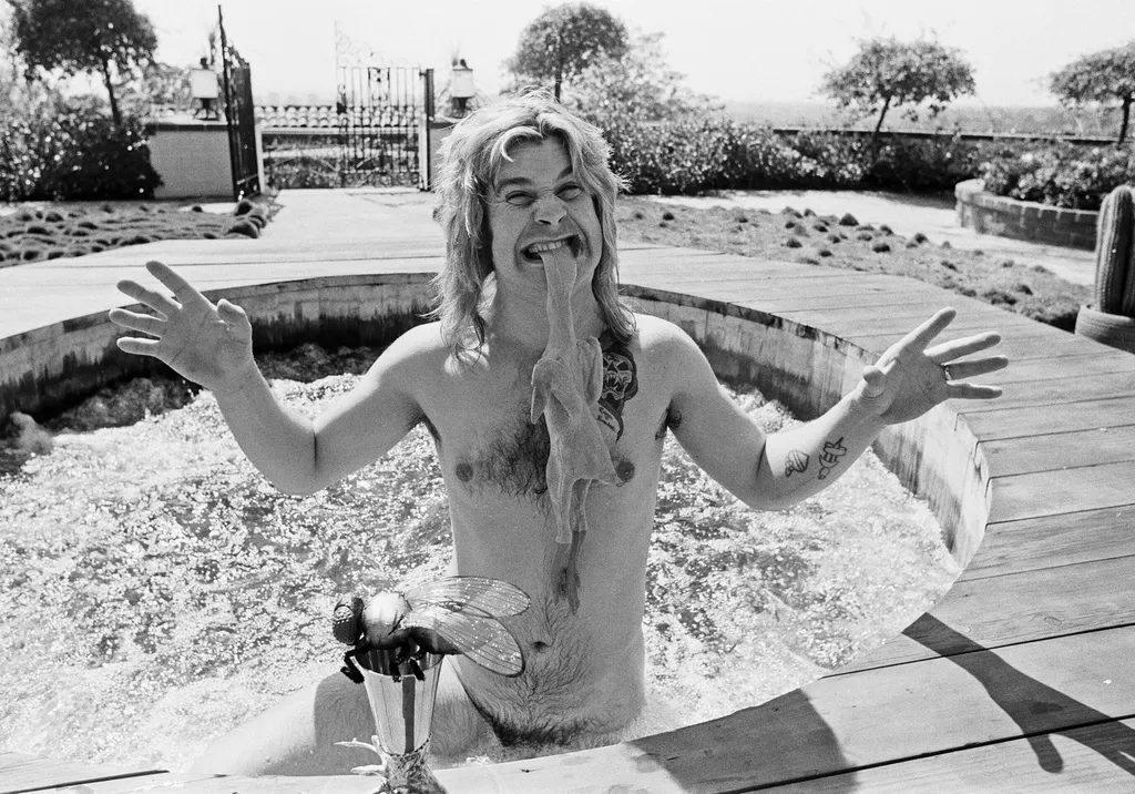 Ozzy Osbourne, former lead singer of Black Sabbath, pictured in his open air hot tub in the garden of his luxury home in Coldwater Canyon Beverly Hills, Los Angeles Biting the head of a rubber chicken.
Picture taken 28th April 1982.
76134ES
Credit Eddi