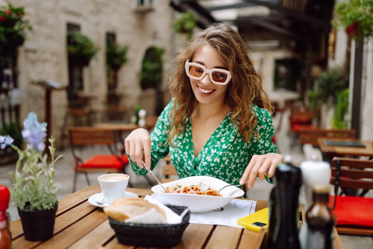 turista nő ebédel egy kisvendéglő kültéri asztalánál