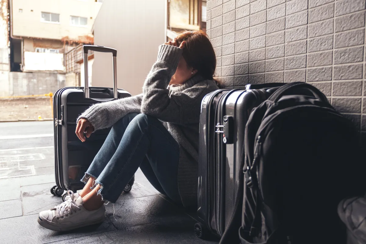 csomagjaival üldögélő gondterhelt turista nő