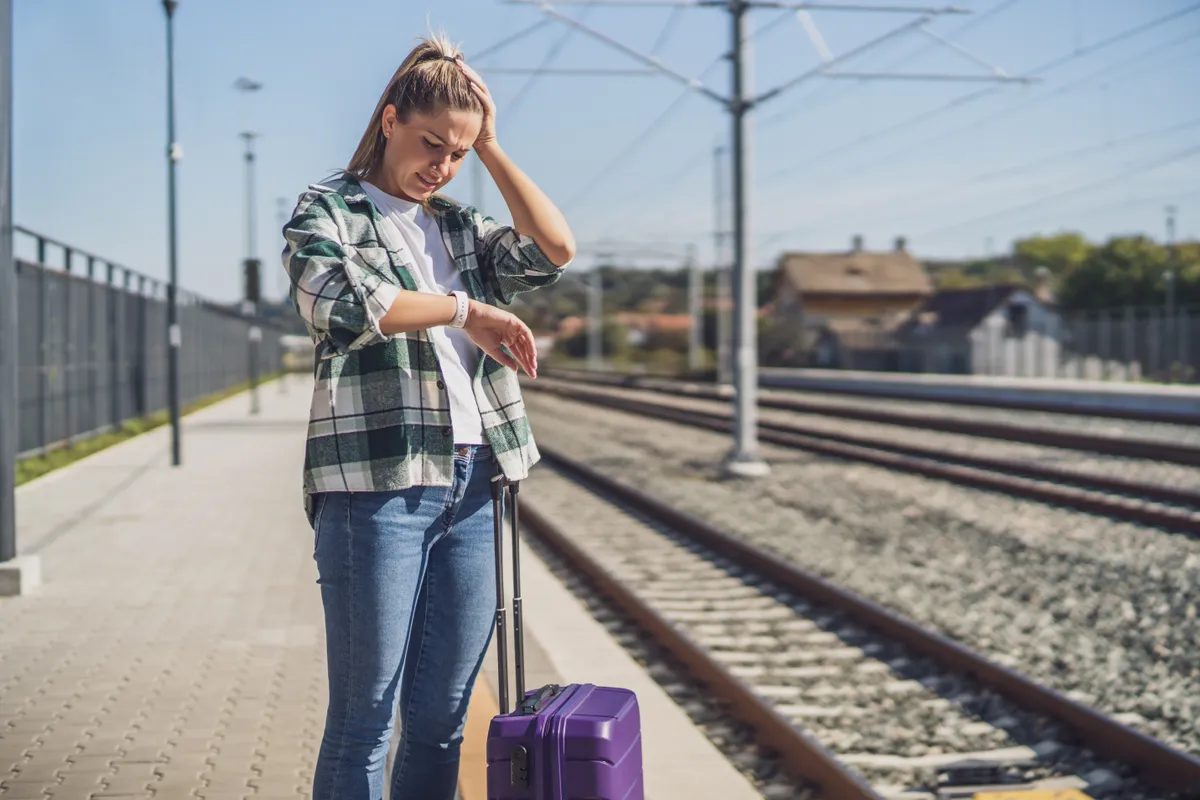 Worried,Woman,Looking,At,Her,Clock,While,Standing,With,Suitcase