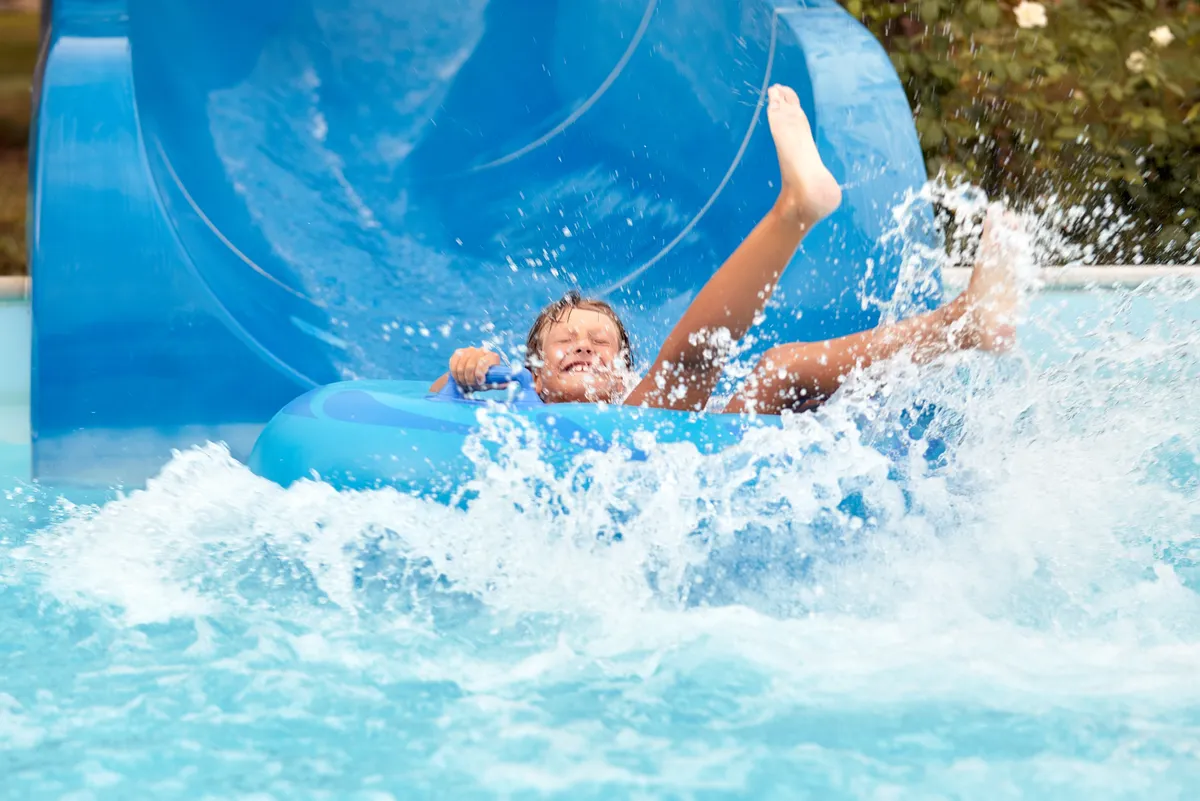 Joyful,Boy,In,Swimming,Goggles,Slides,Down,The,Blue,Water