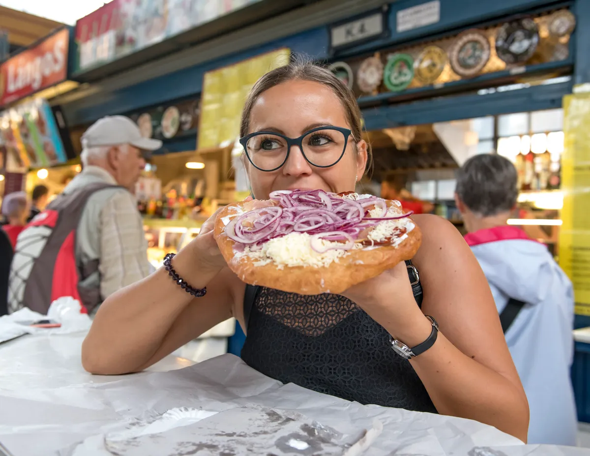 lángos, nő lángost eszik, lilahagyma, sajt, tejföl, piac