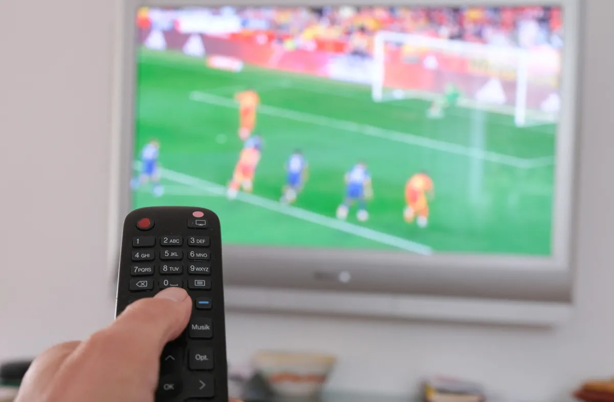 távirányító, tévében foci megy, kanapé