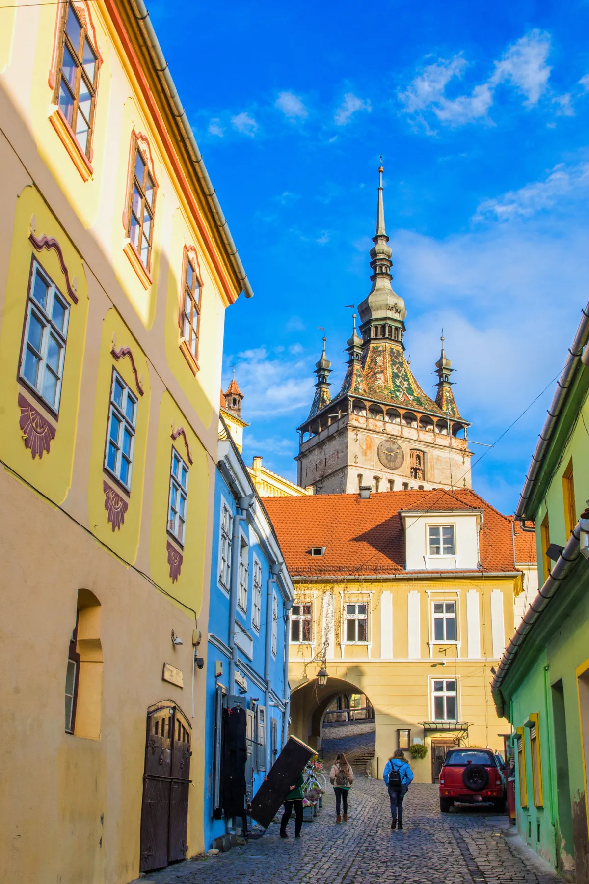 Tourists,Walking,On,A,Cobblestone,Street,Between,Colorful,Buildings,Under