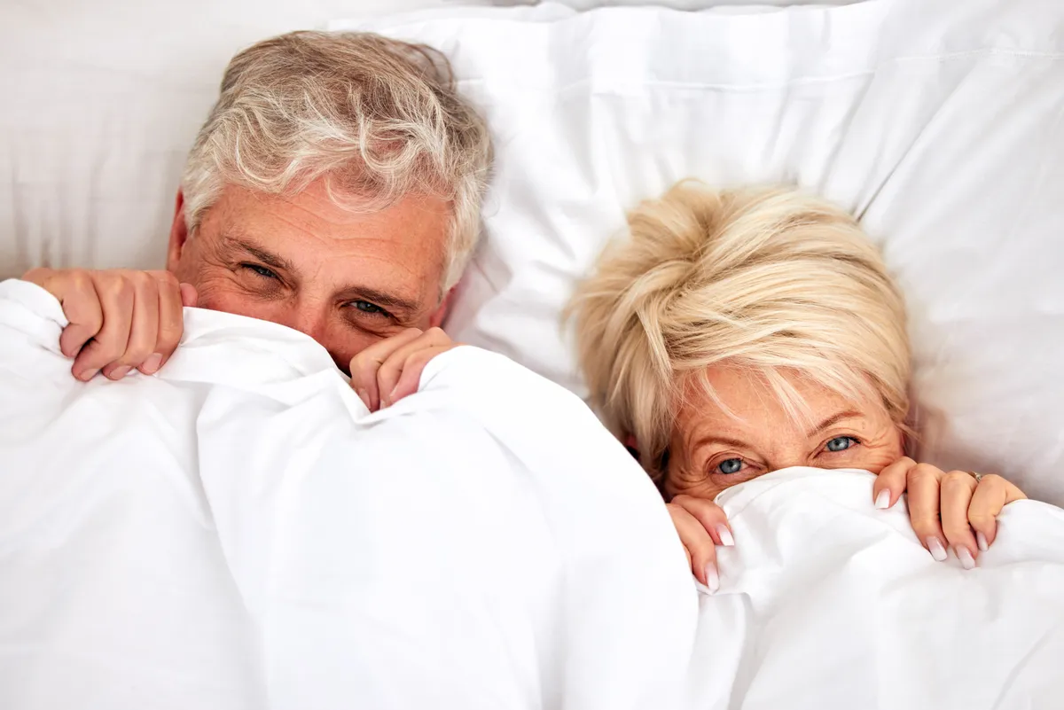 Idős férfi és nő fehér takaró alatt menopauza idején