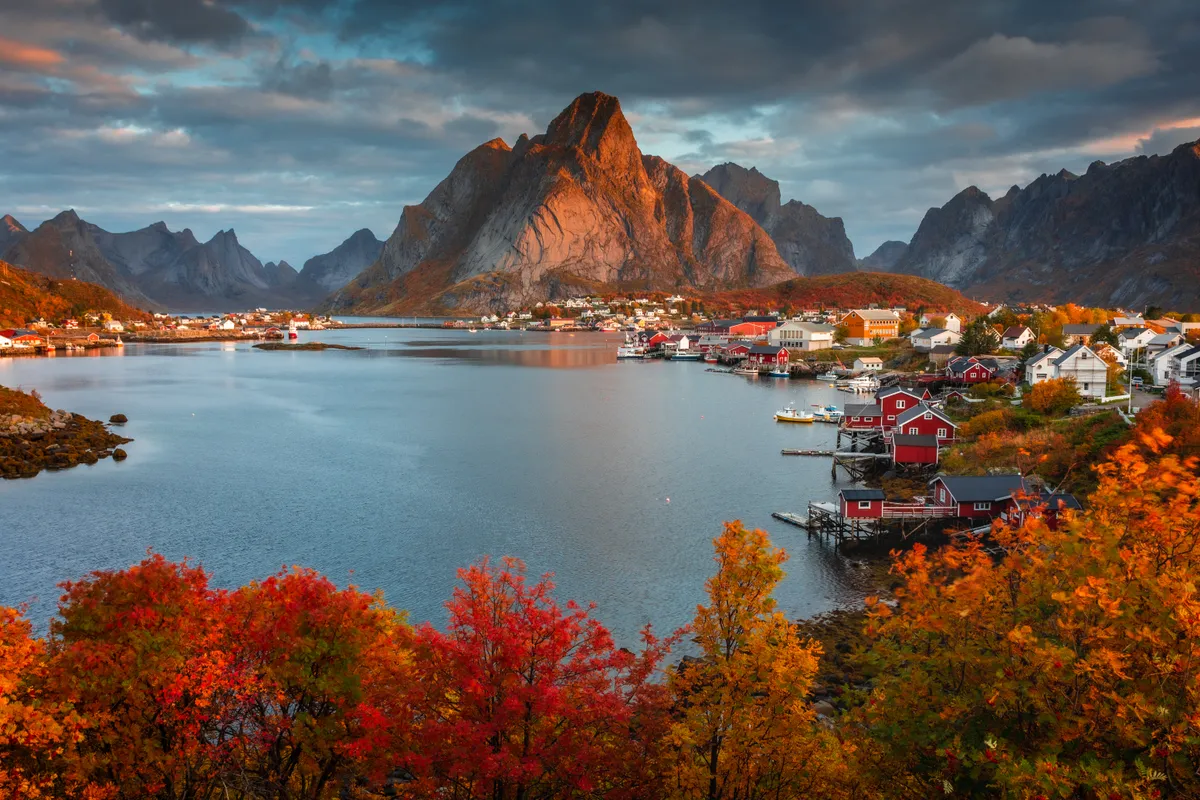 Lofoten, Norvégia, őszi tájkép hegyekkel, halászhajókkal, faluval