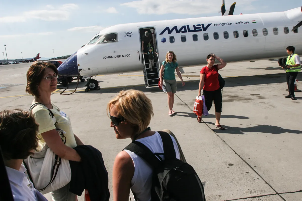 Utasok egy Malév-gép előtt a budapesti Ferihegyi Repülőtéren