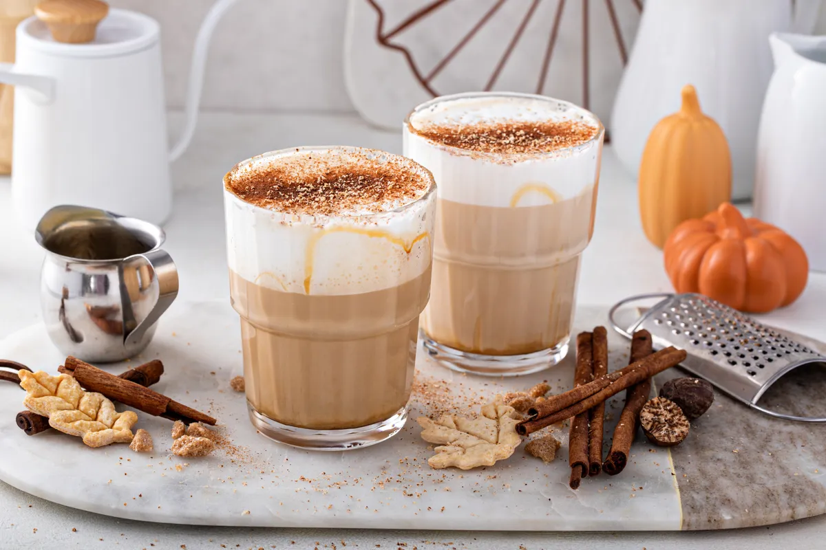 Egy csésze fahéjas latte tálcán, mellette fahéjjal és dísztökkel