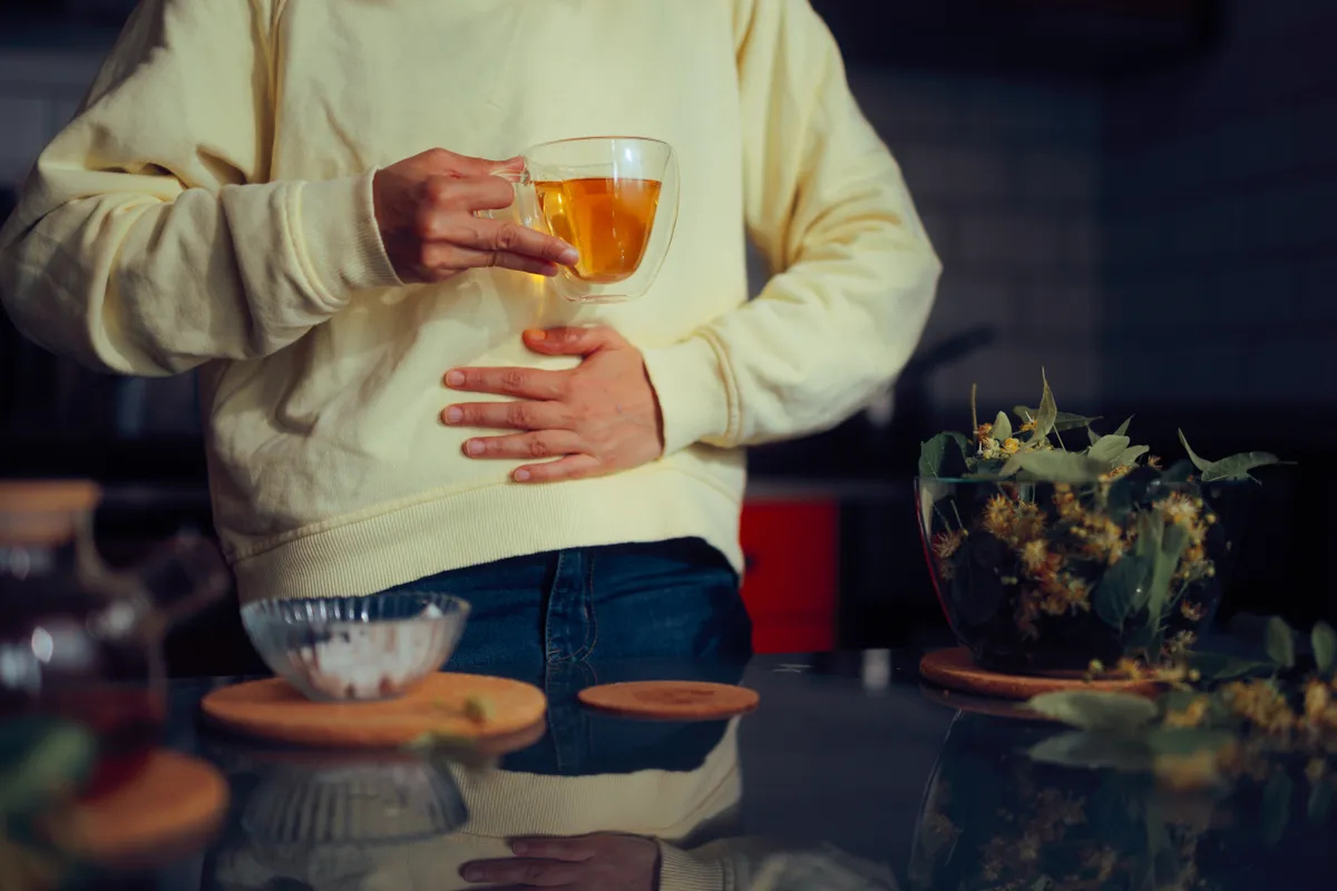 Sárga pulóveres nő puffadás elleni gyógyteát tart a kezében
