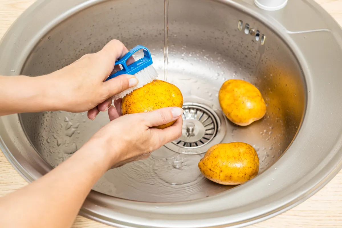 Housewife,Washes,Fresh,Potatoes,In,The,Kitchen,Sink.,Housewife,Peels
