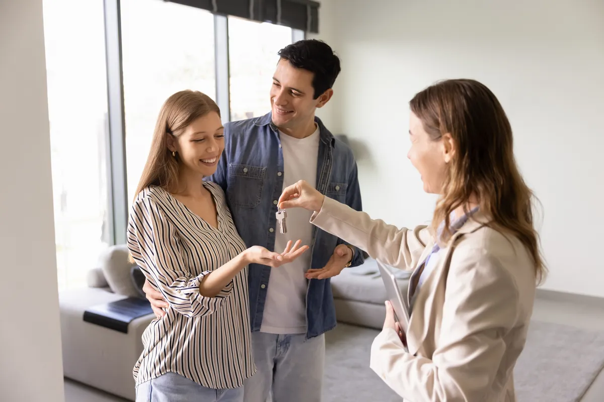 Real,Estate,Agent,Woman,Giving,Key,To,Young,Couple,Of, Otthon Start app,
